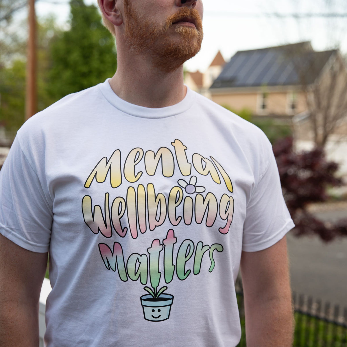 Person wearing a white t-shirt with 'Mental Wellbeing Matters' text and graphic.