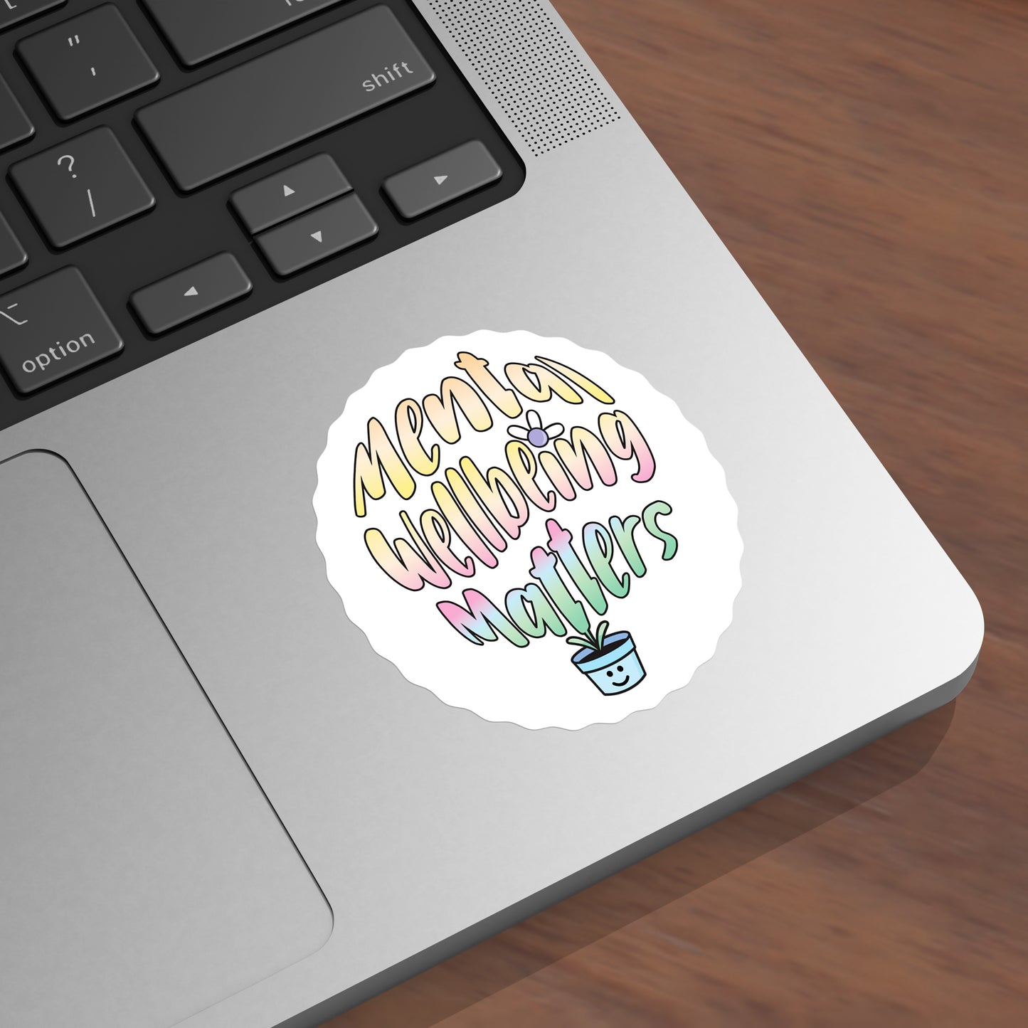 Laptop with a 'Mental Wellbeing Matters' sticker on a wooden surface