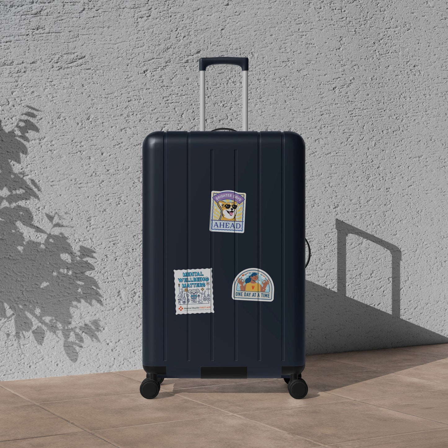 Black suitcase with stickers against a light gray wall